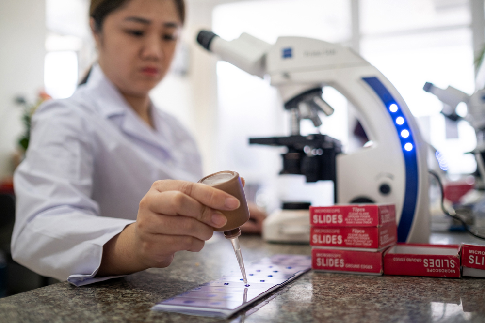 A technician prepares a microscopic slide in a laboratory